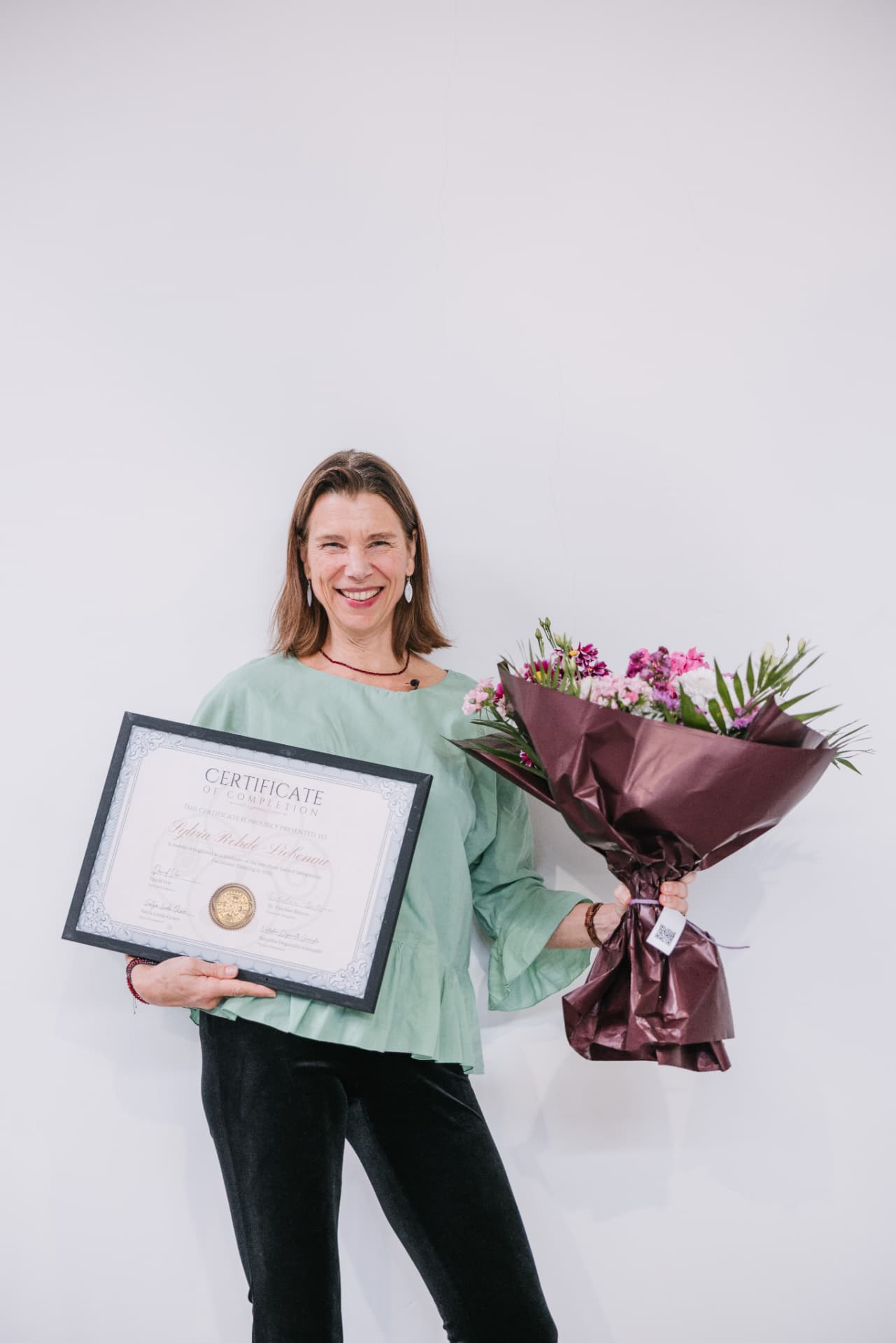 Sylvia holding flowers and her certificate of completion